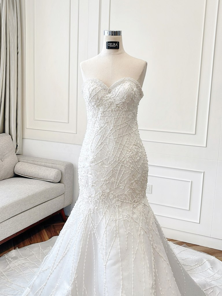 Crystal-beaded mermaid wedding gown with long train on a mannequin by CELRA