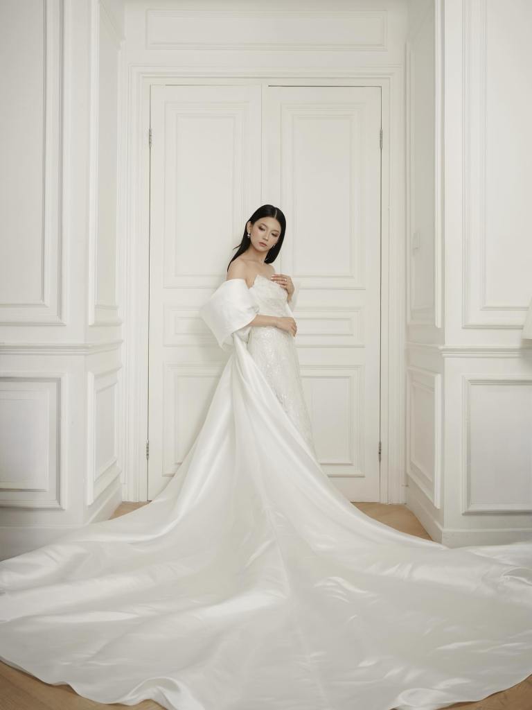 Satin wedding gown with long train in a white panelled room by CELRA