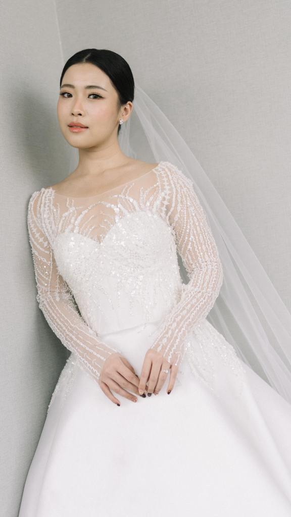 Bride in a long-sleeve beaded lace wedding gown with tulle veil by CELRA