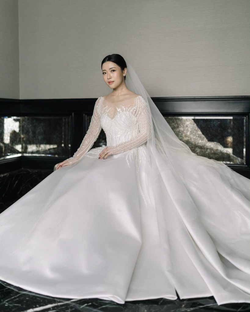 Bride seated in a satin ball gown with cathedral veil by CELRA